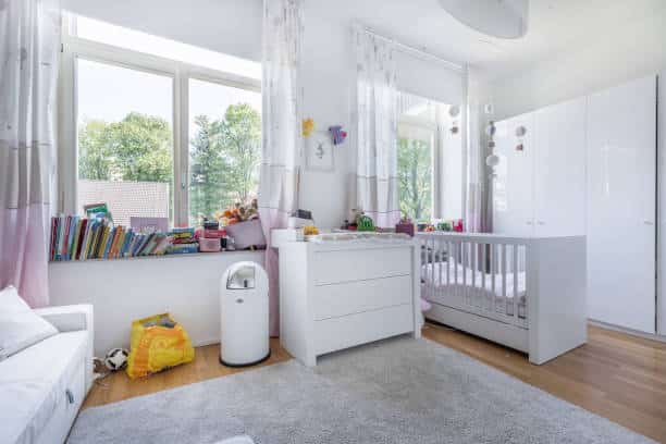 Chambre de bébé fonctionnelle avec lit à barreaux, table à langer, tapis et espace de jeux