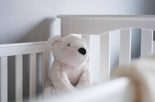 Gros plan sur un ours en peluche blanc dans un lit de bébé