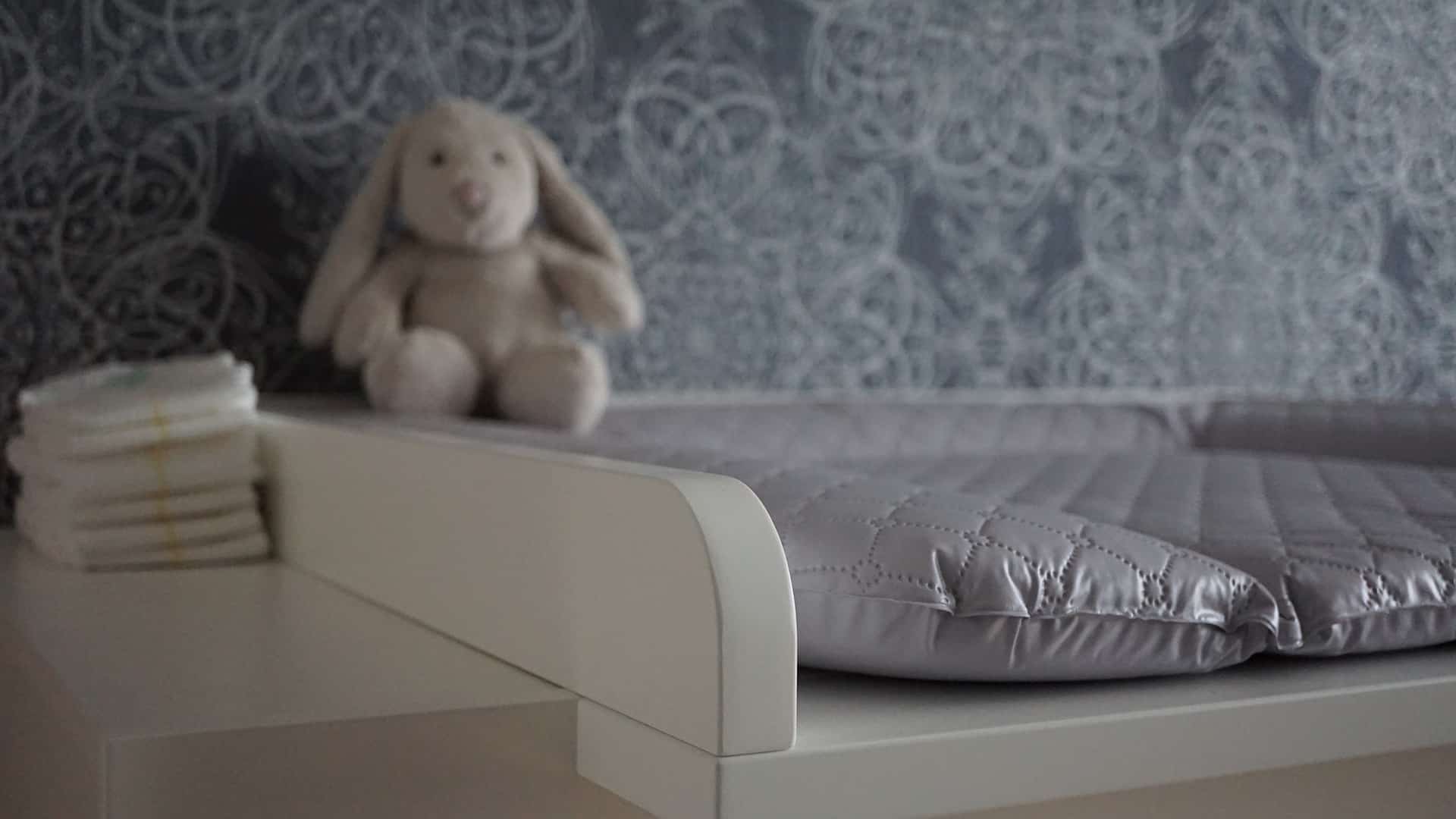 Chambre de bébé avec une table à langer et une peluche lapin